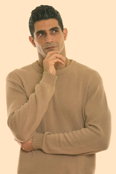 Studio shot of young muscular Persian man thinking with hand on chin — Stock Photo, Image