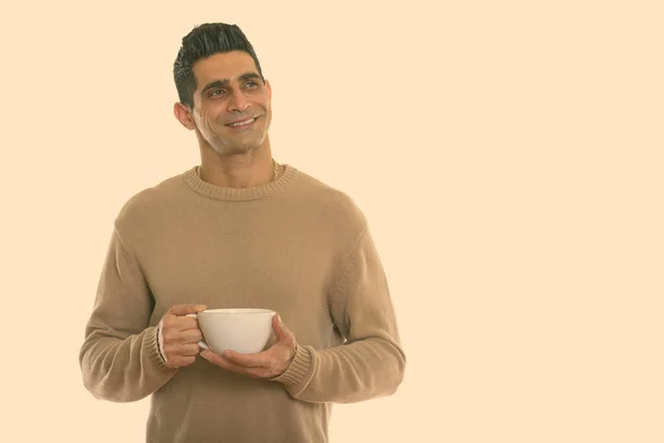 Підстрелений молодиком, радісний перський чоловік, який посміхається і думає, поки тримає чашку кави. — стокове фото