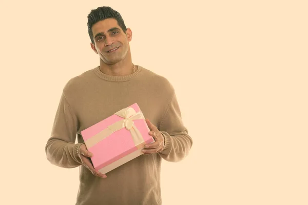 Στιγμιότυπο στούντιο του νεαρού ευτυχισμένου Πέρση άνδρα χαμογελώντας κρατώντας κουτί δώρου — Φωτογραφία Αρχείου