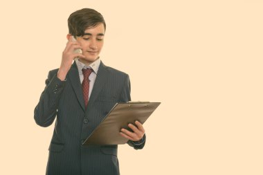 Genç ve yakışıklı İranlı iş adamının, panoya bakarken cep telefonuyla konuştuğu bir stüdyo fotoğrafı.