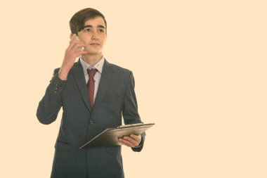 Genç ve yakışıklı İranlı iş adamının cep telefonuyla konuşurken ve pano tutarken çekilmiş bir fotoğrafı.