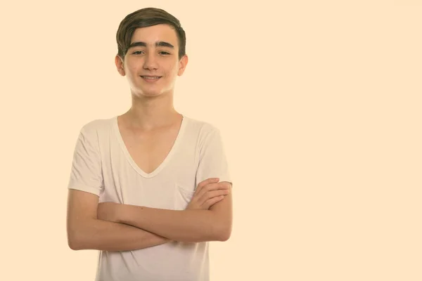 Studio shot of young happy Persian teenage boy smiling with arms crossed — Stock Photo, Image