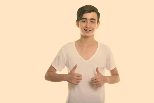 Studio shot van jong gelukkig Perzisch tiener jongen glimlachen terwijl het geven van duimen omhoog — Stockfoto