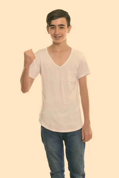 Studio shot of young happy Persian teenage boy smiling and standing while looking motivated — Stock Photo, Image