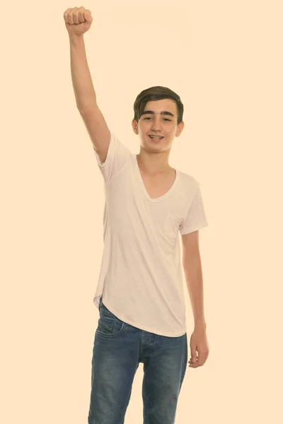 Studio shot of young happy Persian teenage boy smiling with arm raised — Stock Photo, Image