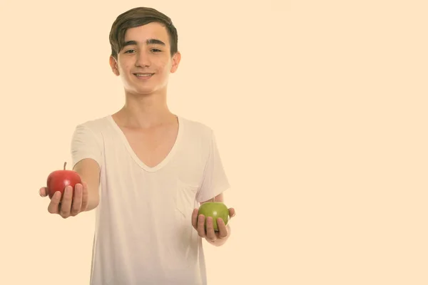 Studio colpo di giovane felice ragazzo adolescente persiano sorridente mentre dà mela rossa e tenendo mela verde — Foto Stock