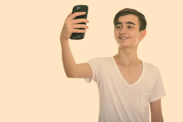 Estúdio tiro de jovem feliz adolescente persa sorrindo ao tirar foto selfie com telefone celular — Fotografia de Stock