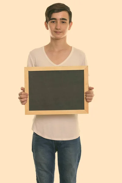 工作室拍摄年轻英俊的波斯少年拿着空白黑板站在那里 — 图库照片