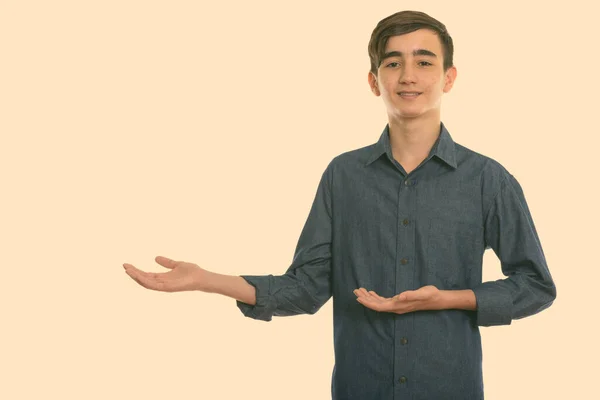 Studio colpo di giovane felice ragazzo adolescente persiano sorridente mentre mostra qualcosa — Foto Stock