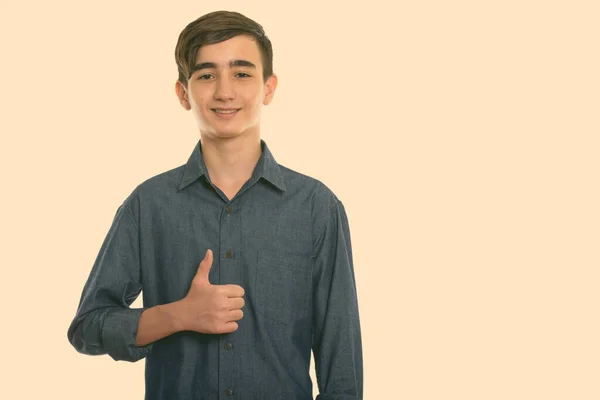 Estudio disparo de joven feliz adolescente persa sonriendo mientras que da pulgar hacia arriba —  Fotos de Stock