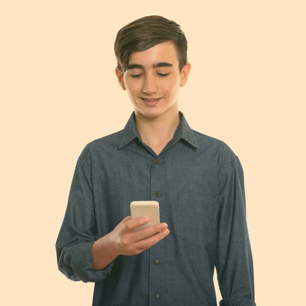 工作室拍摄的年轻快乐的波斯少年在使用手机时微笑的照片 — 图库照片