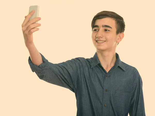 Estúdio tiro de jovem feliz adolescente persa sorrindo ao tirar foto selfie com telefone celular — Fotografia de Stock