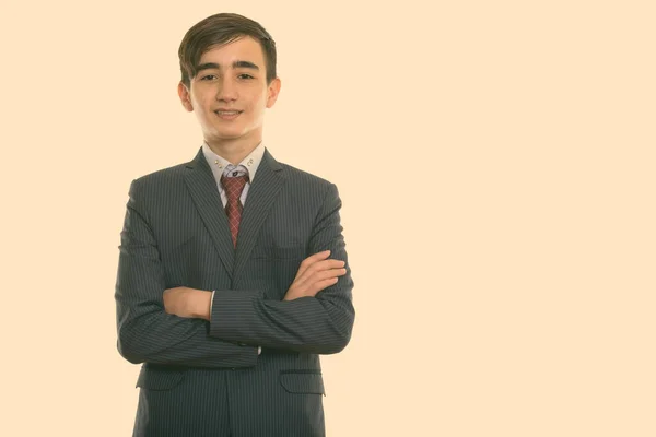 Studio shot of young happy Persian adolescent homme d'affaires souriant avec les bras croisés — Photo