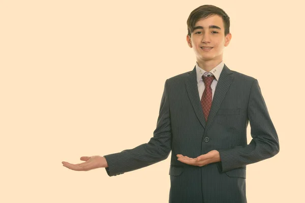 Studio colpo di giovane felice persiano adolescente uomo d'affari sorridente mentre mostra qualcosa — Foto Stock