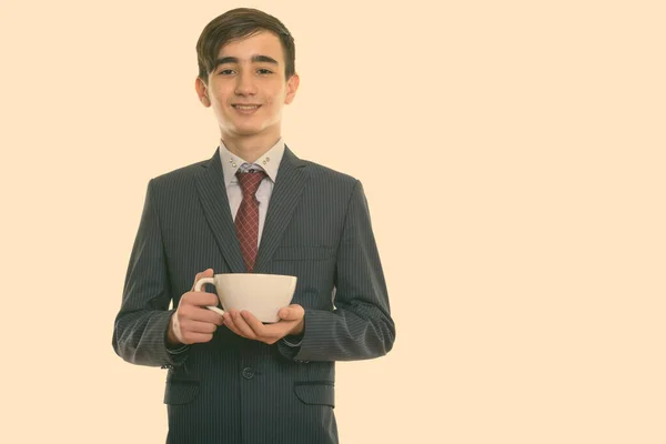 Studioaufnahme eines jungen glücklichen persischen Geschäftsmannes, der lächelt, während er eine Kaffeetasse in der Hand hält — Stockfoto