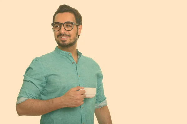 Giovane uomo indiano felice che tiene la tazza di caffè mentre pensa — Foto Stock