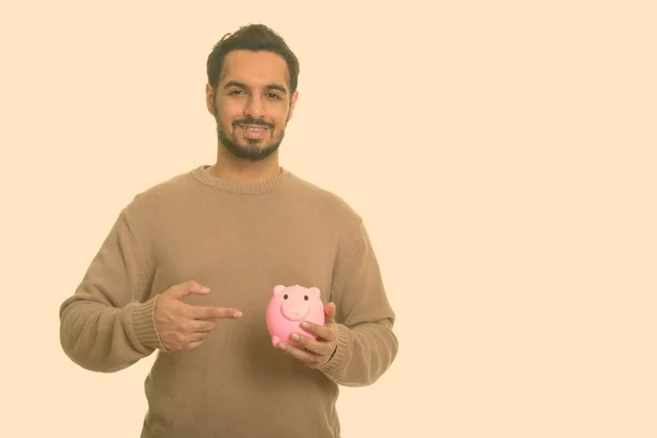 Joven indio feliz sosteniendo alcancía y señalando el dedo — Foto de Stock