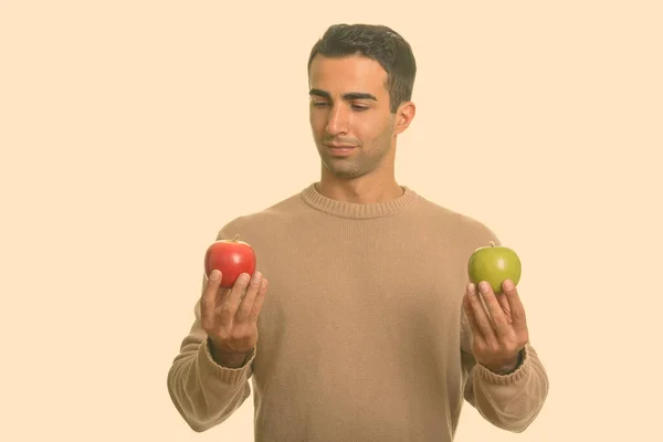 Joven hombre iraní guapo elegir entre manzana roja y verde — Foto de Stock