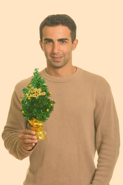 Jeune homme iranien heureux tenant Joyeux arbre de Noël prêt pour Noël — Photo