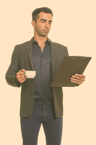 年轻英俊的伊朗商人拿着咖啡杯看剪贴板 — 图库照片