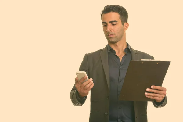 Jeune homme d'affaires iranien beau tenant téléphone portable et presse-papiers — Photo