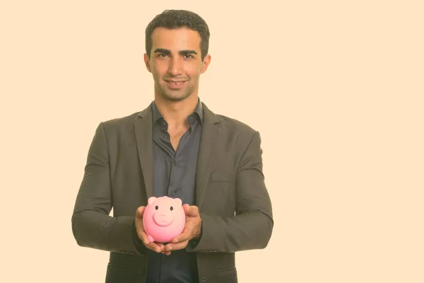 Young happy Iranian businessman holding piggy bank — Stock Photo, Image