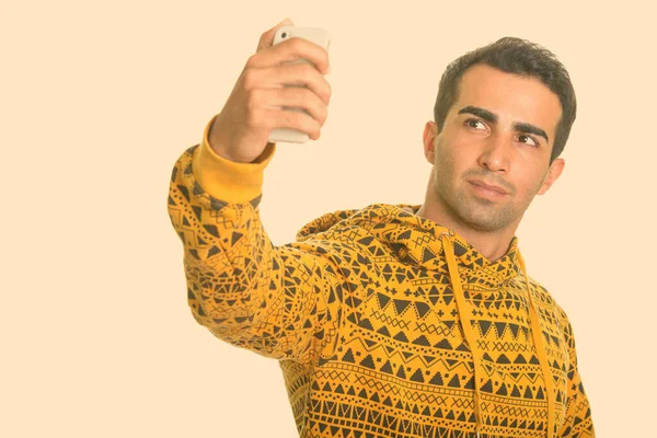 Young handsome Iranian man taking selfie with mobile phone