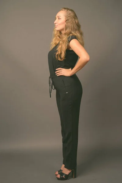 Молодая красивая деловая женщина с длинными волнистыми светлыми волосами на сером фоне — стоковое фото