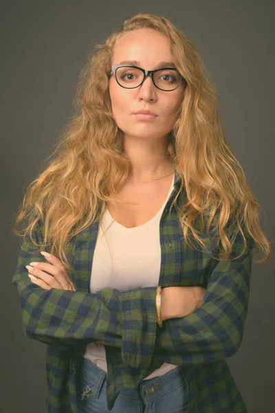 Giovane bella donna con lunghi capelli biondi ondulati su sfondo grigio — Foto Stock