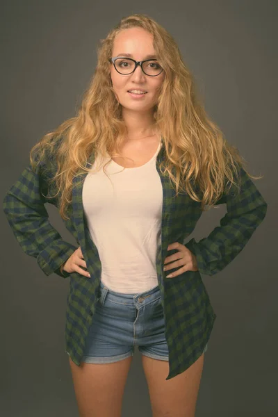 Young beautiful woman with long wavy blond hair against gray background — Stock Photo, Image