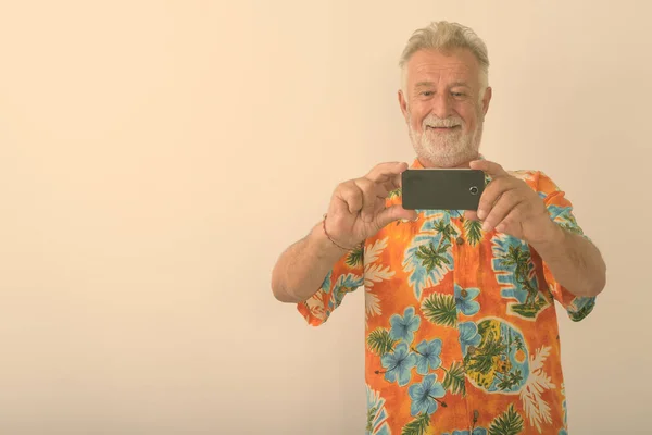 Beyaz Arka Planda Cep Telefonuyla Fotoğraf Çekilirken Gülümseyen Yaşlı Turistin — Stok fotoğraf