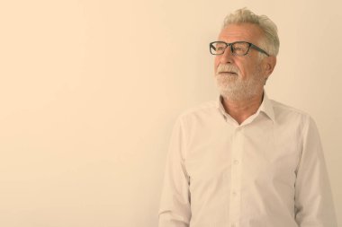 Beyaz arka planda gülümseyen ve düşünen yaşlı sakallı adamın stüdyo fotoğrafı.