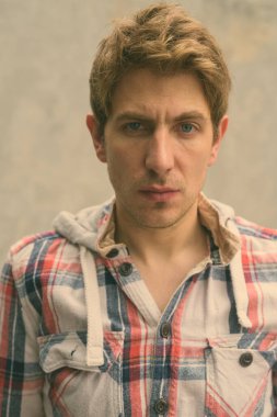 Sokaklarda beton duvara yaslanmış sarı saçlı yakışıklı bir adamın portresi.