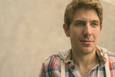 Sokaklarda beton duvara yaslanmış sarı saçlı yakışıklı bir adamın portresi.