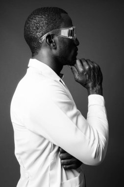 Kahverengi arka planda koruyucu gözlük takan yakışıklı Afrikalı doktorun stüdyo fotoğrafı.