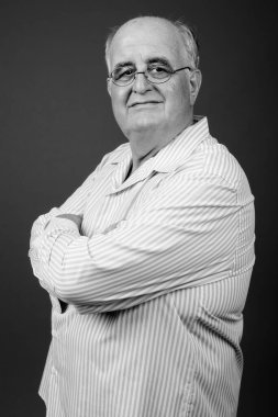 Kahverengi arka planda gözlük takan şişman bir adamın stüdyo fotoğrafı.