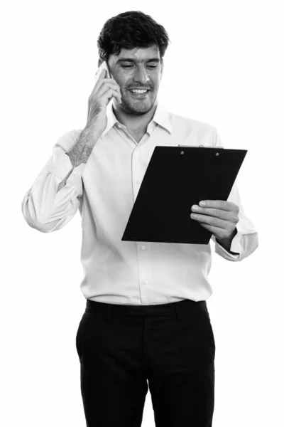 Jovem feliz empresário persa sorrindo e lendo na área de transferência enquanto fala no telefone móvel — Fotografia de Stock