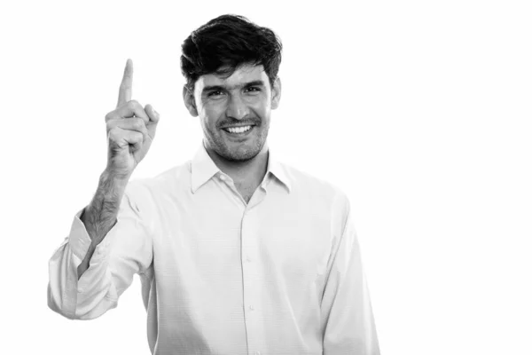 Studioaufnahme eines jungen glücklichen persischen Geschäftsmannes, der lächelnd mit erhobenem Zeigefinger lächelt — Stockfoto
