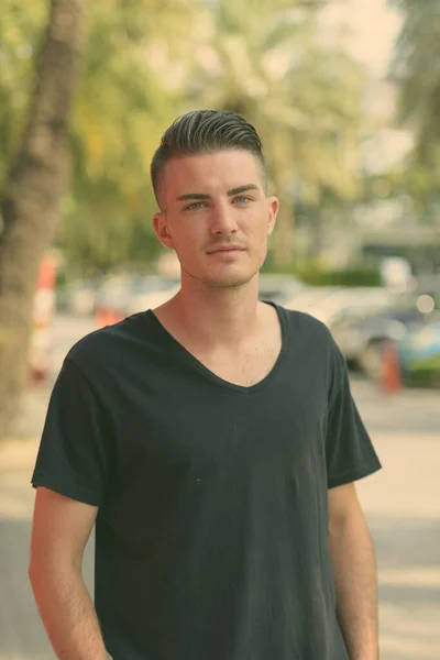 Junger schöner Mann schaut auf dem Parkplatz in die Kamera — Stockfoto