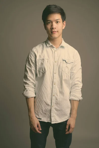 Young handsome Asian businessman wearing white shirt against gray background — Stock Photo, Image