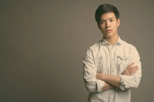 Junger hübscher asiatischer Geschäftsmann trägt weißes Hemd vor grauem Hintergrund — Stockfoto