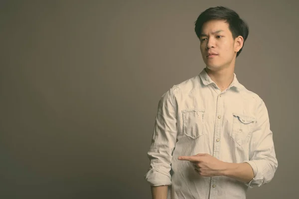 Гарний азіатський бізнесмен у білій сорочці на сірому фоні. — стокове фото