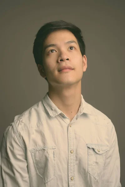 Fiatal jóképű ázsiai üzletember visel fehér inget szürke háttér — Stock Fotó