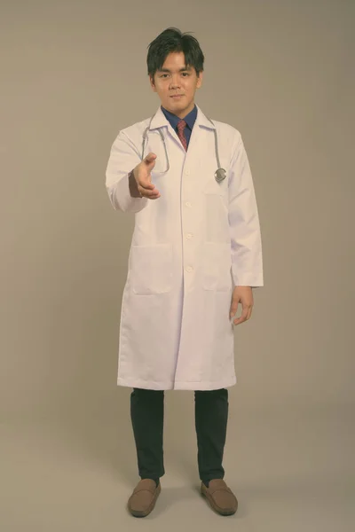 Νεαρός όμορφος Ασιάτης γιατρός με γκρι φόντο — Φωτογραφία Αρχείου