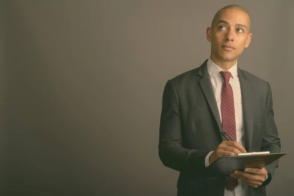 Handsome bald businessman wearing suit against gray background — Stock Photo, Image