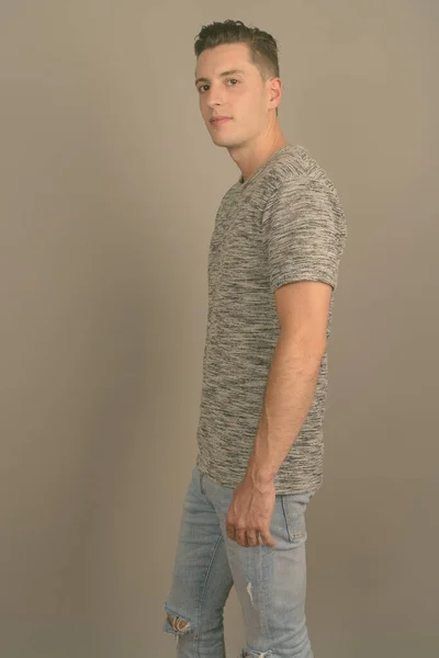 Joven hombre guapo con camisa gris sobre fondo gris — Foto de Stock