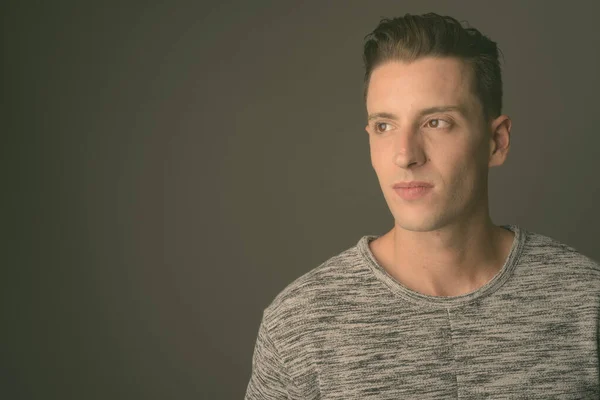 Joven hombre guapo con camisa gris sobre fondo gris — Foto de Stock