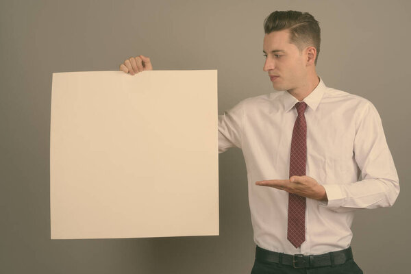 Young handsome businessman against gray background