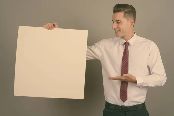 Junger gutaussehender Geschäftsmann vor grauem Hintergrund — Stockfoto