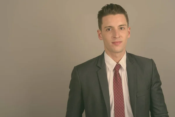 Junger gutaussehender Geschäftsmann im Anzug vor grauem Hintergrund — Stockfoto